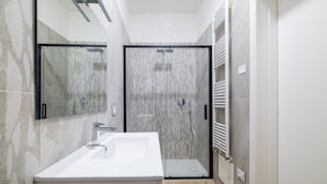A modern bathroom with a large mirror, a white sink, and a shower enclosure. - Due Agosto Apartment Comfy Modern and Central (Bologna)
