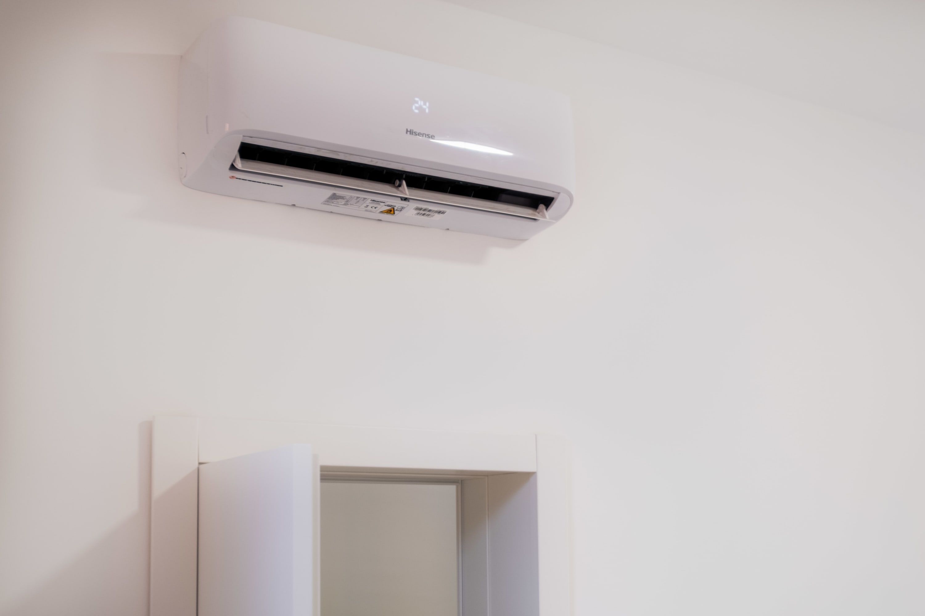A white air conditioning unit mounted on a plain wall.