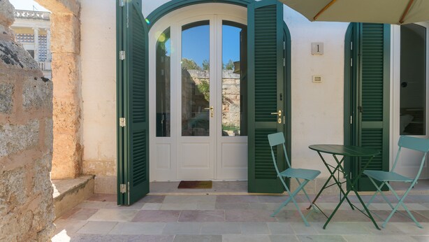 A villa entrance with a white door, green shutters, and a small table with two chairs. - Masseria Pichilicchio 1 by Wonderful Italy (Ostuni)