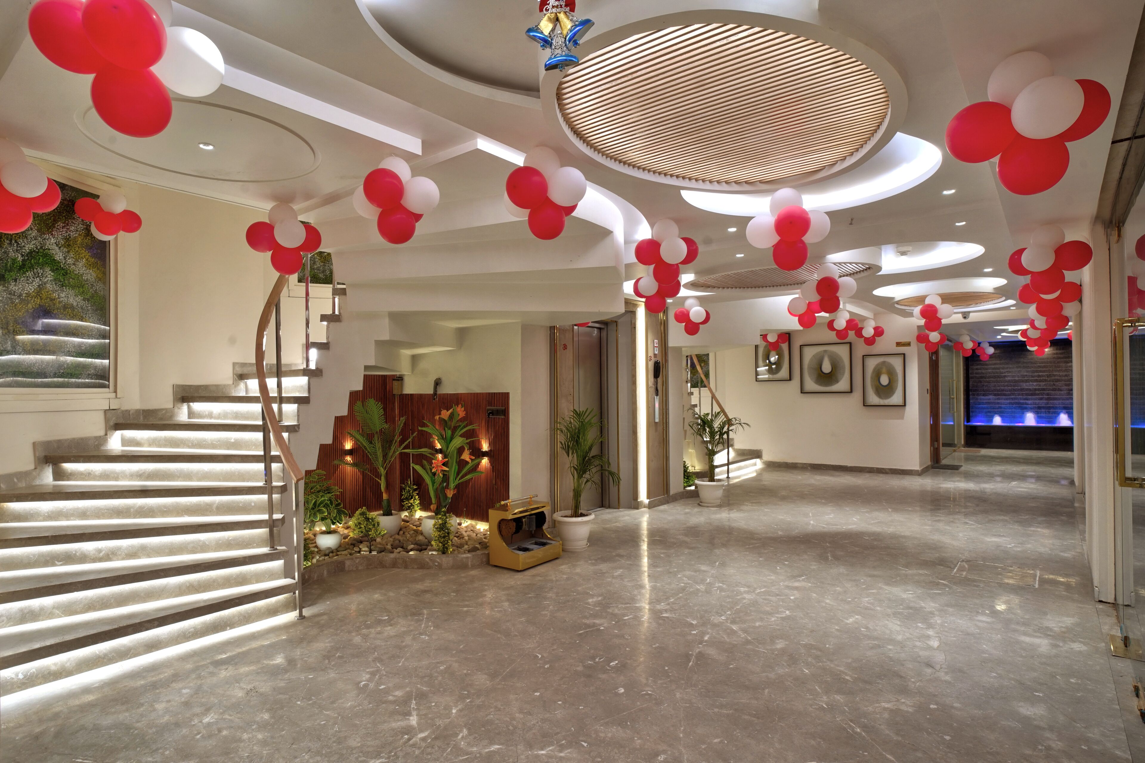 A modern hotel lobby with a marble floor, a staircase, and red and white balloon decorations.