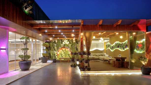 A modern hotel lobby with a central seating area, large potted plants, and a decorative wall. - Gold The Royal (New Delhi)