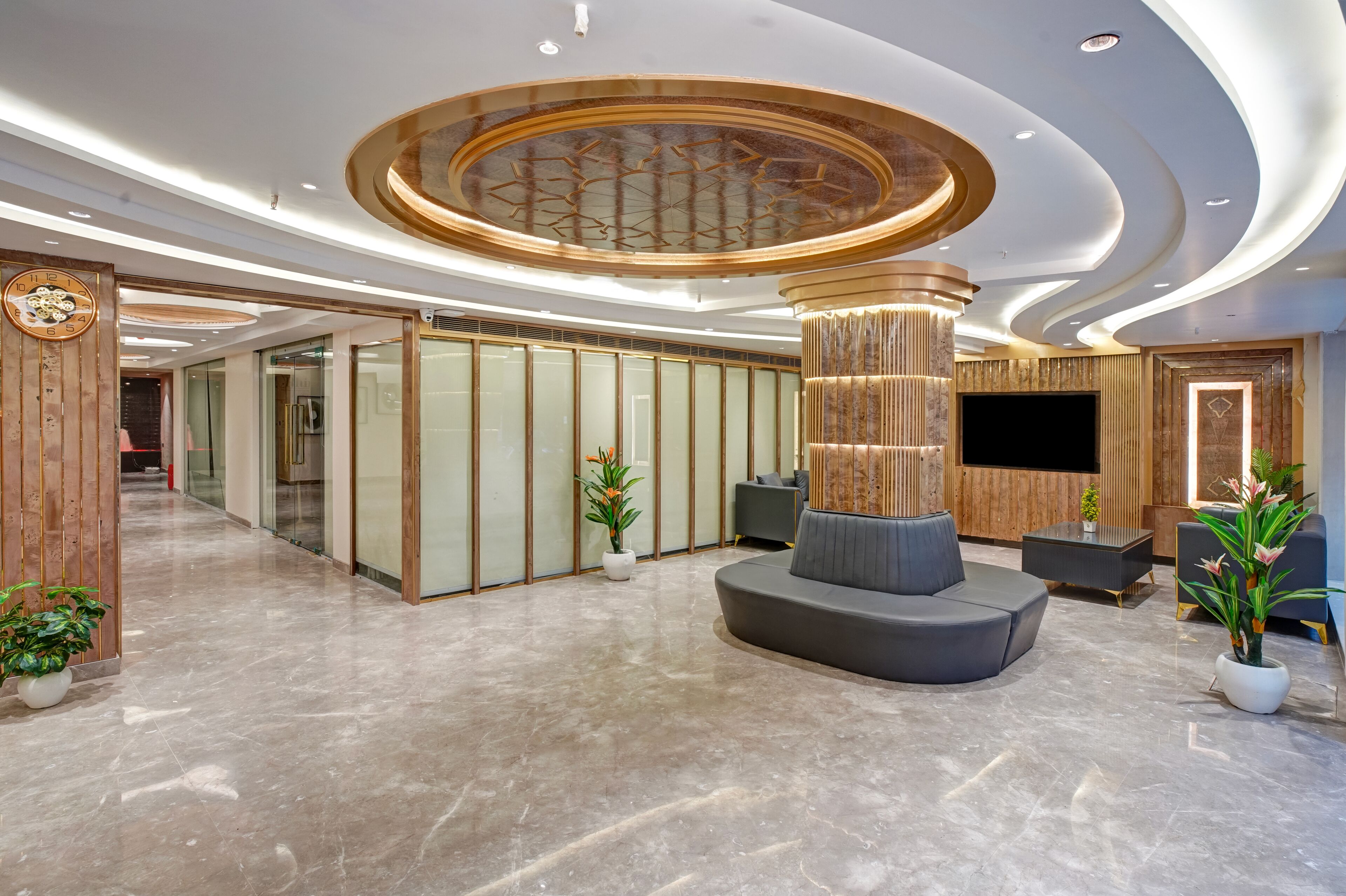 Un lobby moderno con una zona de estar central, un mostrador de recepción y un televisor de pantalla plana grande.