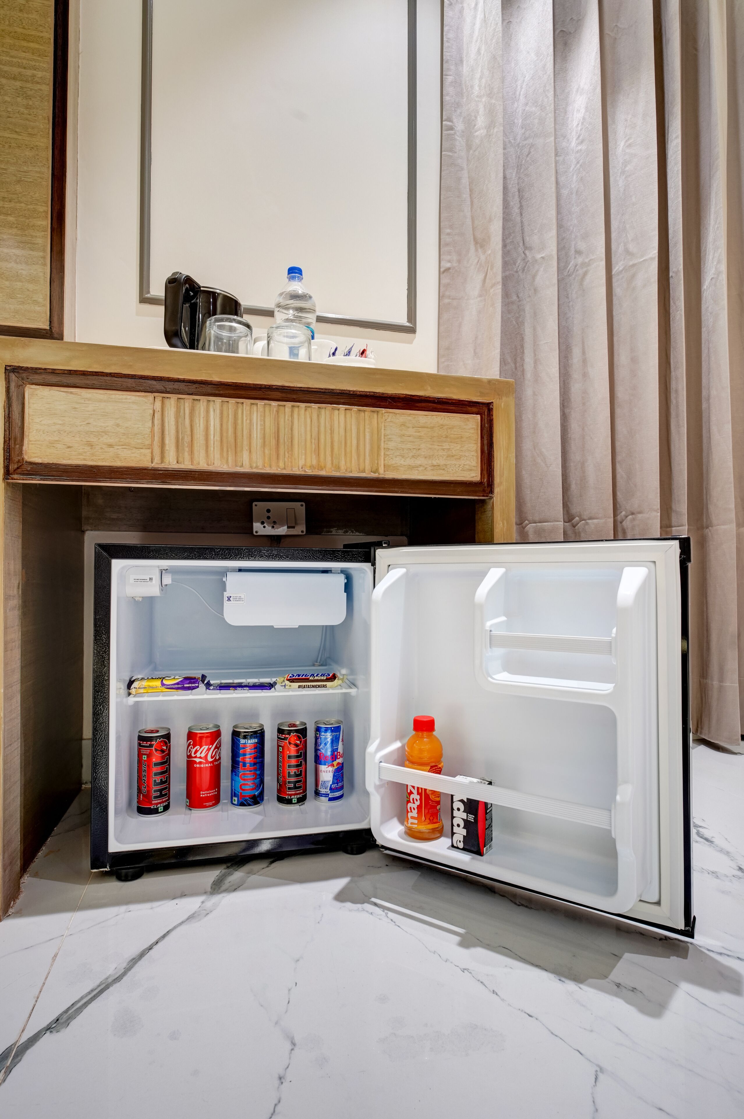 A compact refrigerator with a freezer compartment, containing various beverages and snacks.
