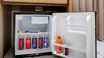 A compact refrigerator with a freezer compartment, containing various beverages and snacks.
