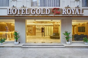 L'esterno dell'Hotel Gold The Royal, con un ingresso imponente, ampie vetrate e piante in vaso.