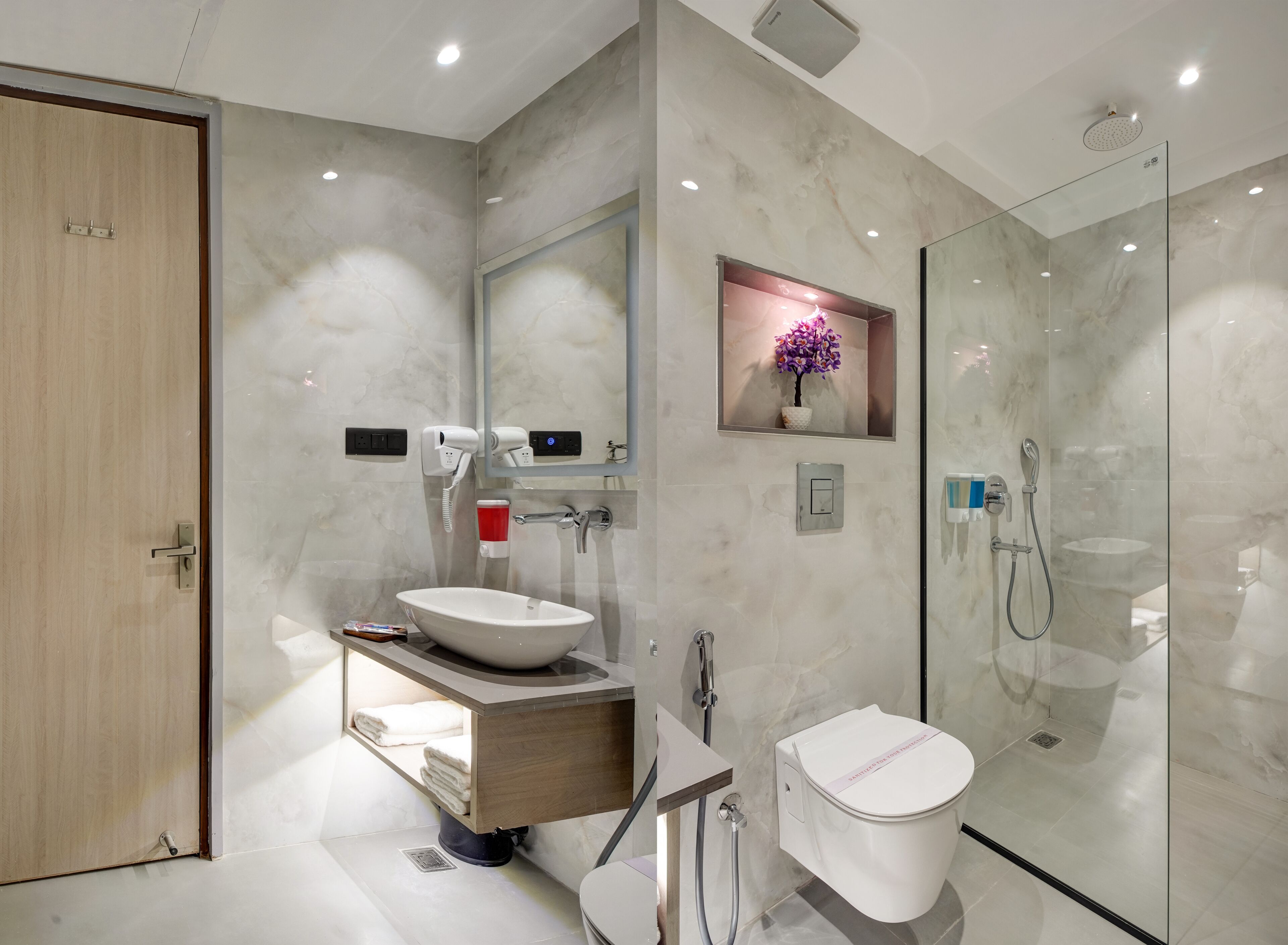 A modern bathroom with a marble sink, a glass shower enclosure, and a toilet.