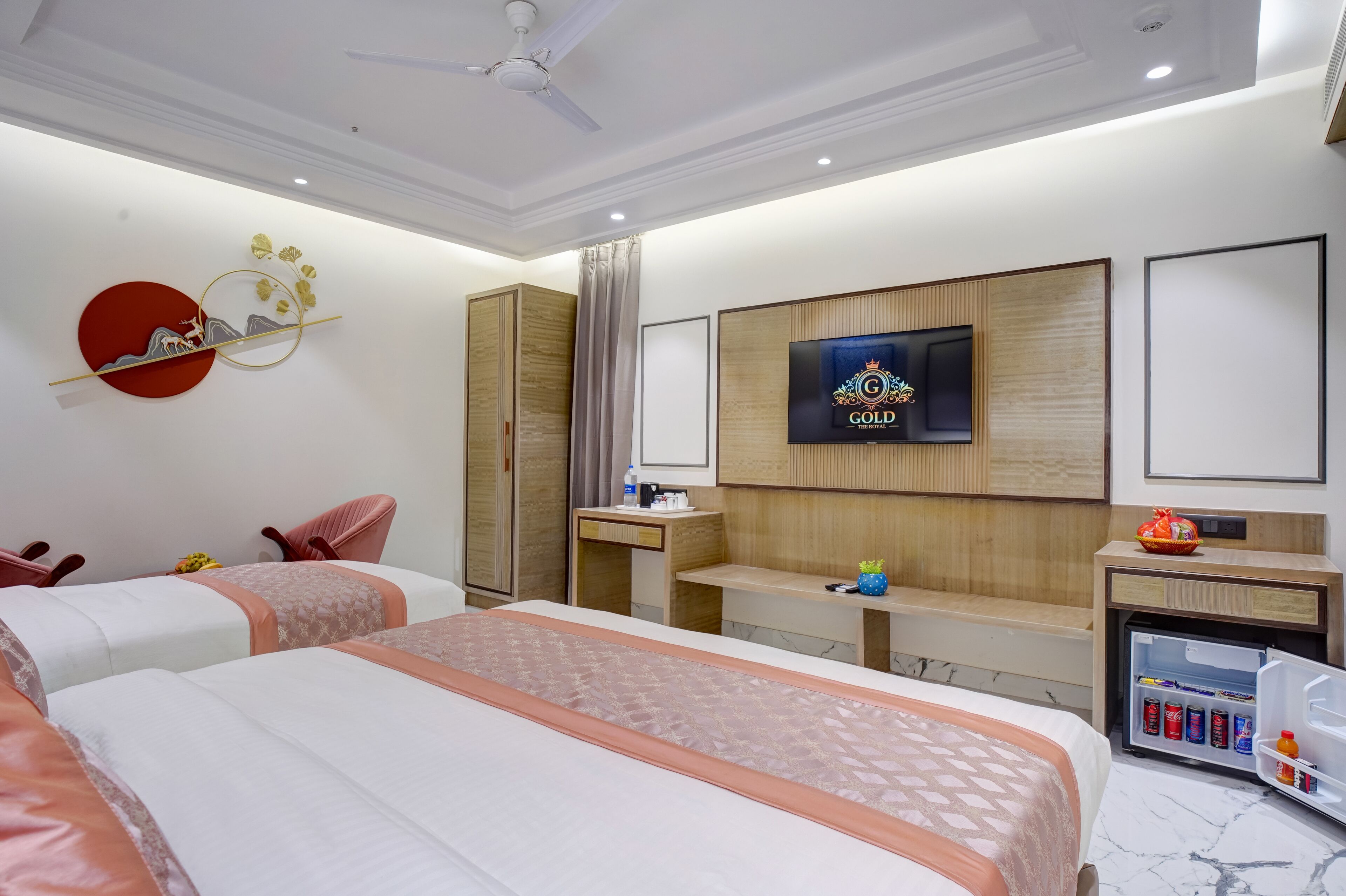 Habitación de hotel con dos camas, televisión, escritorio, minibar y armario.