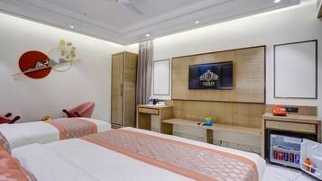 A hotel room with two beds, a TV, a desk, a mini-fridge, and a wardrobe.