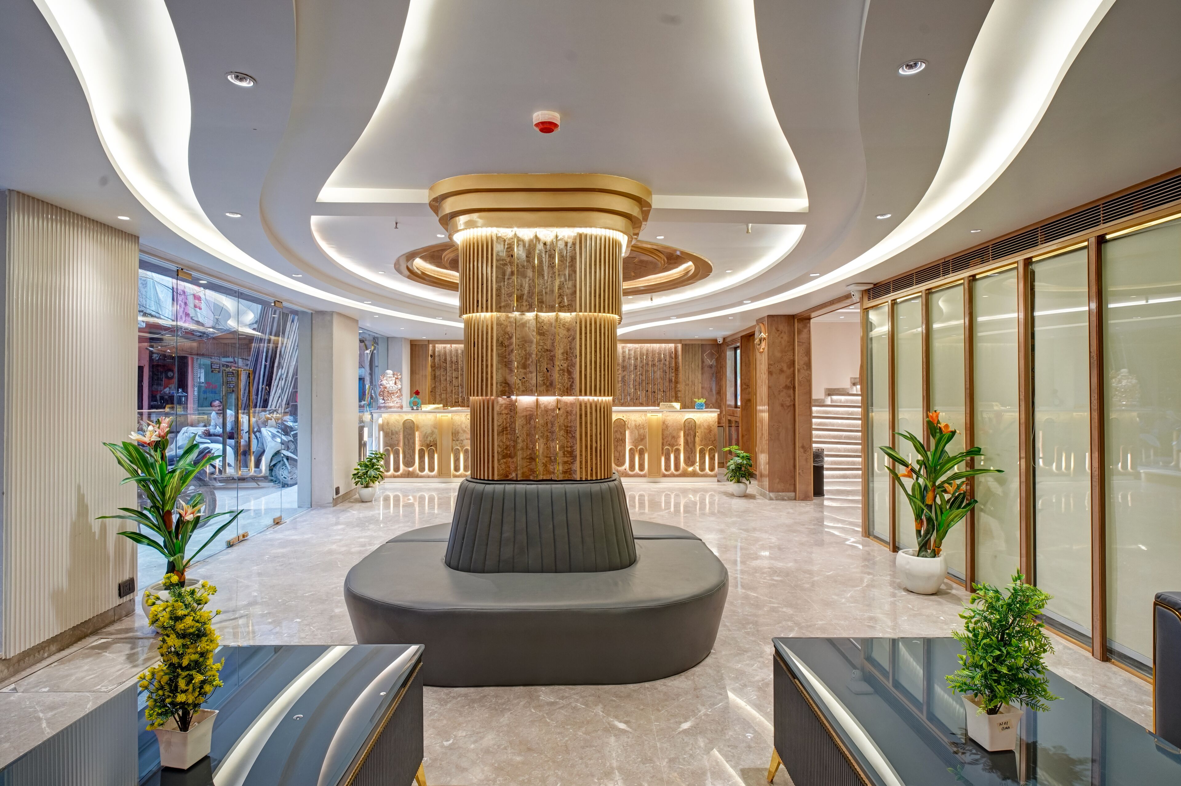 Een moderne lobby met een centrale kolom, zithoeken en potplanten.