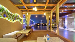 A restaurant with wooden beams, marble tables, and a wall of greenery. - Gold The Royal (New Delhi)