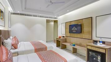 A hotel room with two beds, a TV, a desk with a refrigerator, and a small seating area.