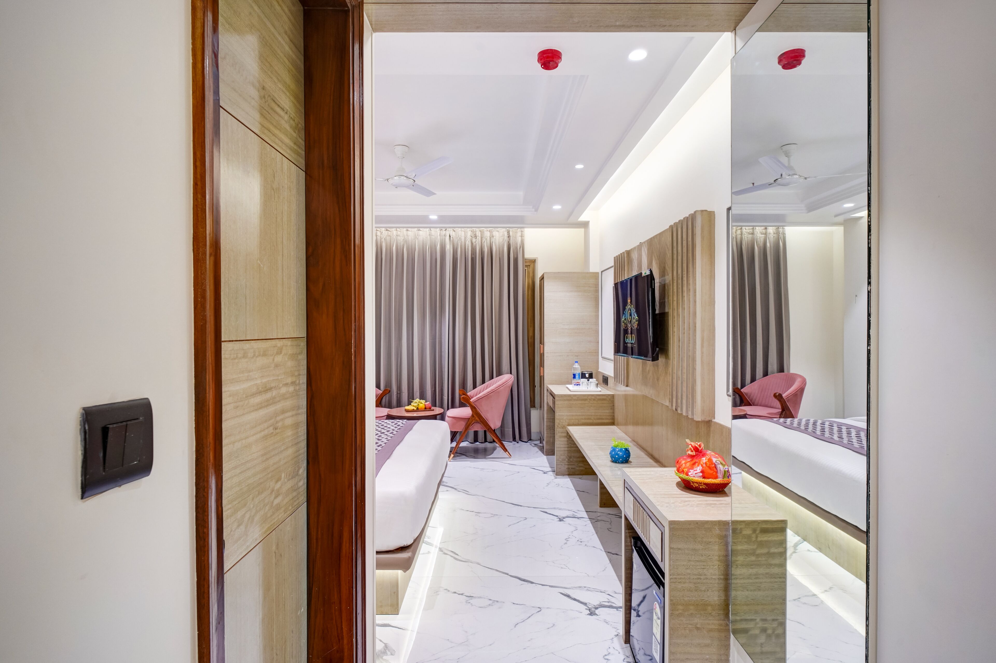 A modern hotel room with a large mirror, a bed, a desk, and a chair.