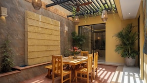 Un patio con mesa y sillas de madera, rodeado de muros de piedra y macetas con plantas.