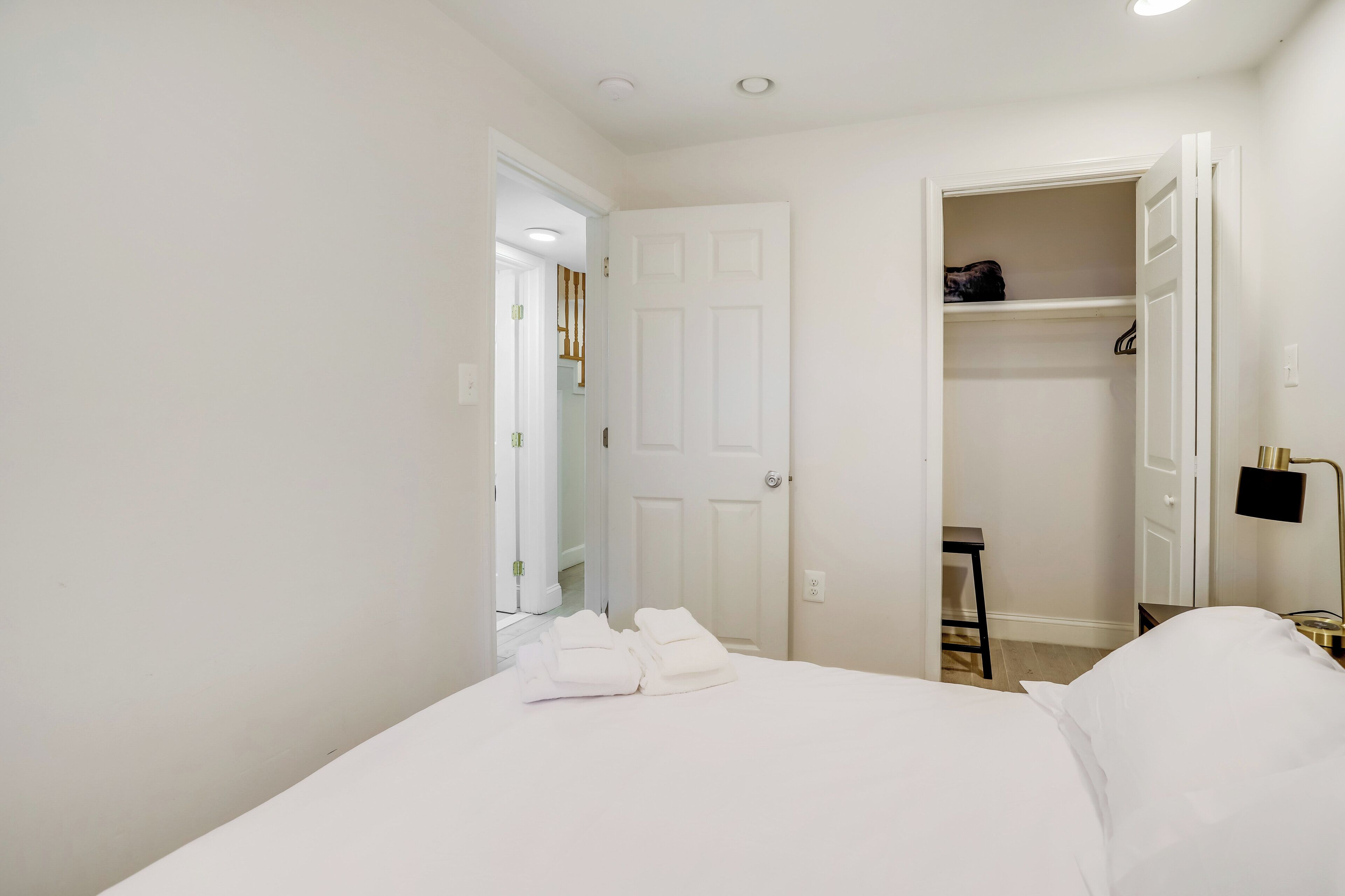 Ein Hotelzimmer mit Bett, Schrank und Schreibtisch mit Lampe.