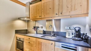 A kitchen with wooden cabinets, a stainless steel sink, a coffee maker, and a toaster.