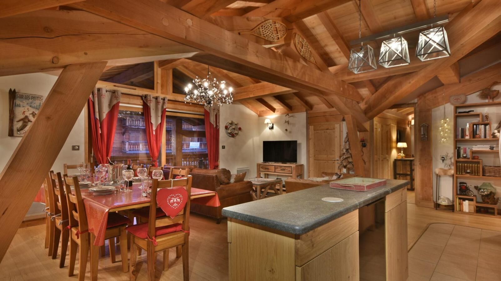 A spacious loft with a dining area, kitchen, and living space, featuring exposed wooden beams and a cozy ambiance.