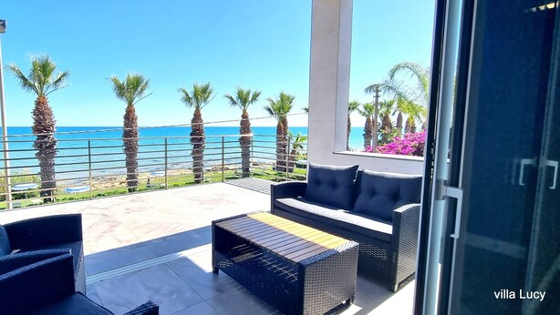 Un balcón con vista al mar, amueblado con un sofá y una mesa de centro.