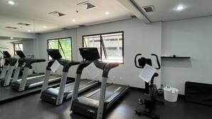 A gym with treadmills, a stationary bike, and a mirror. - Get a flat-1504 Berrini 4 estrelas (São Paulo)