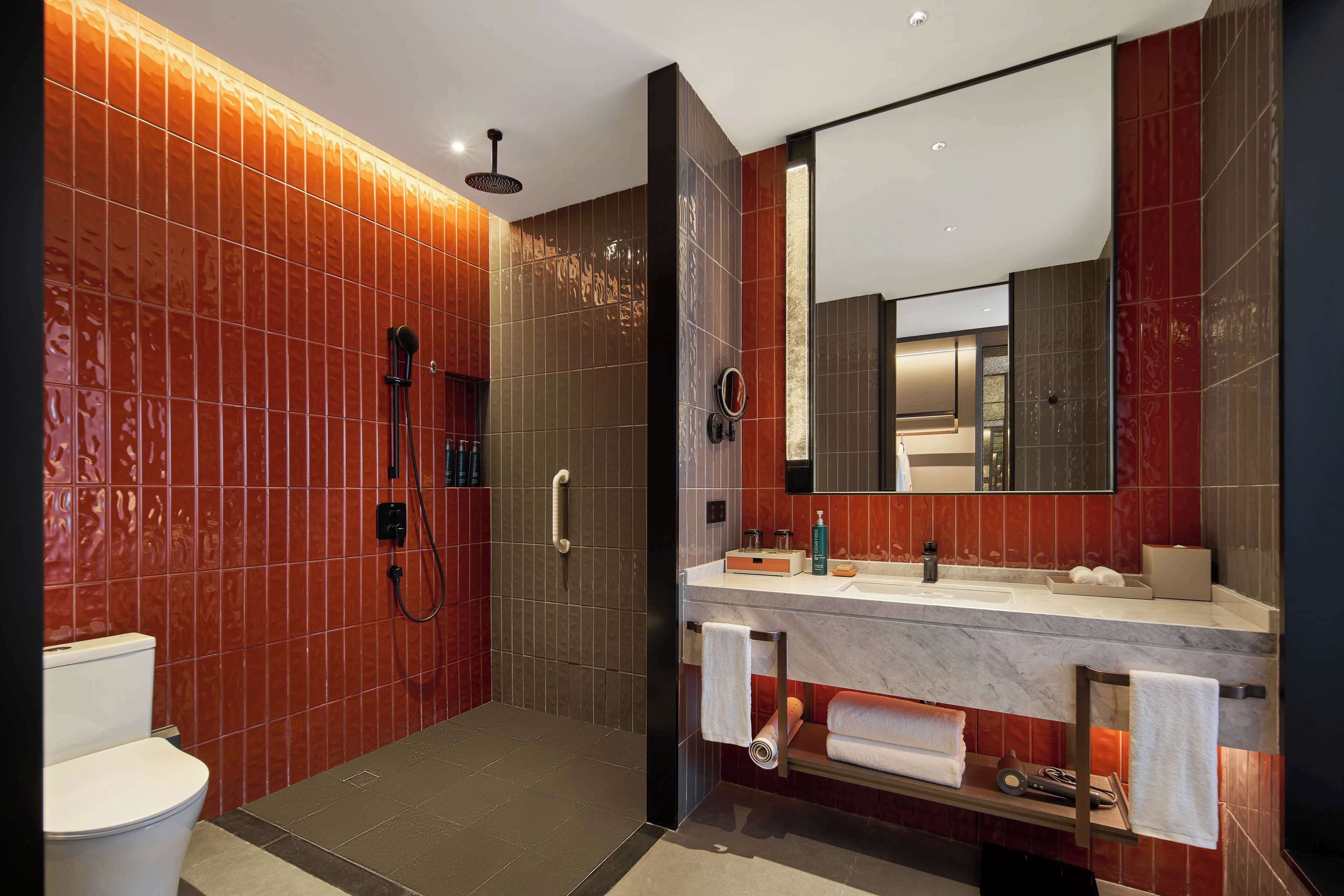 A modern bathroom with a glass-enclosed shower, a white toilet, and a marble sink with a large mirror.