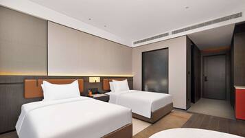 A hotel room with two beds, a desk, a nightstand, and a red cabinet.