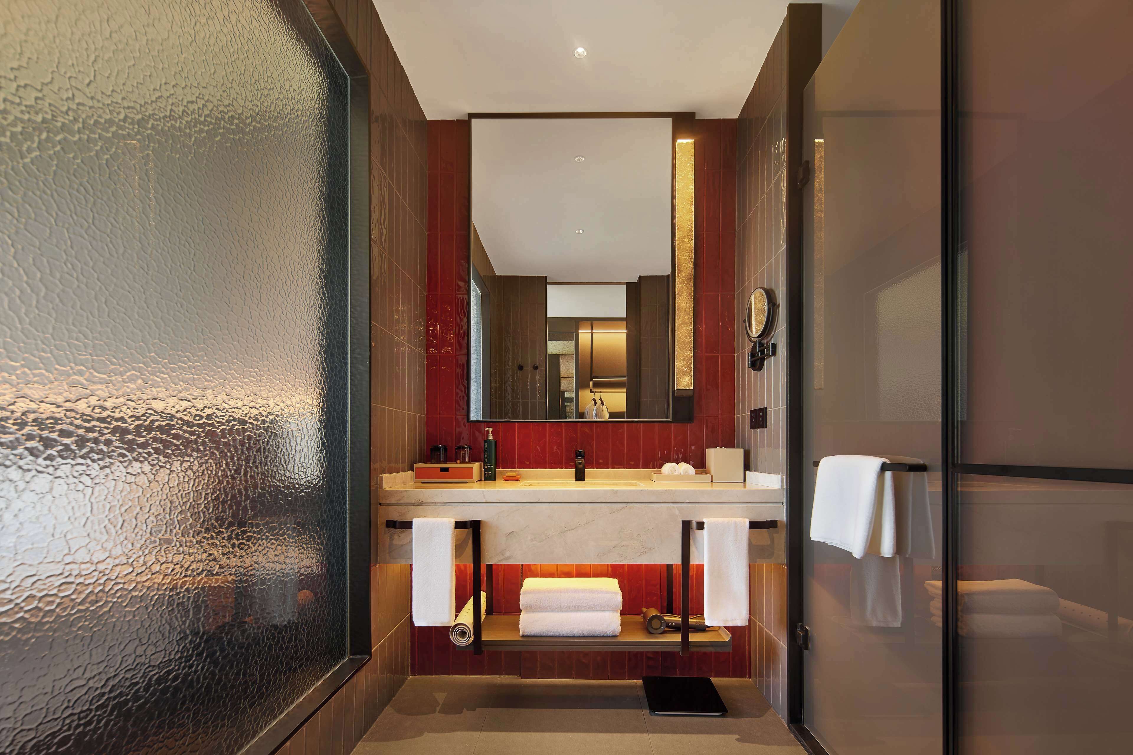Un baño moderno con cabina de ducha de vidrio, tocador de mármol y un espejo grande.
