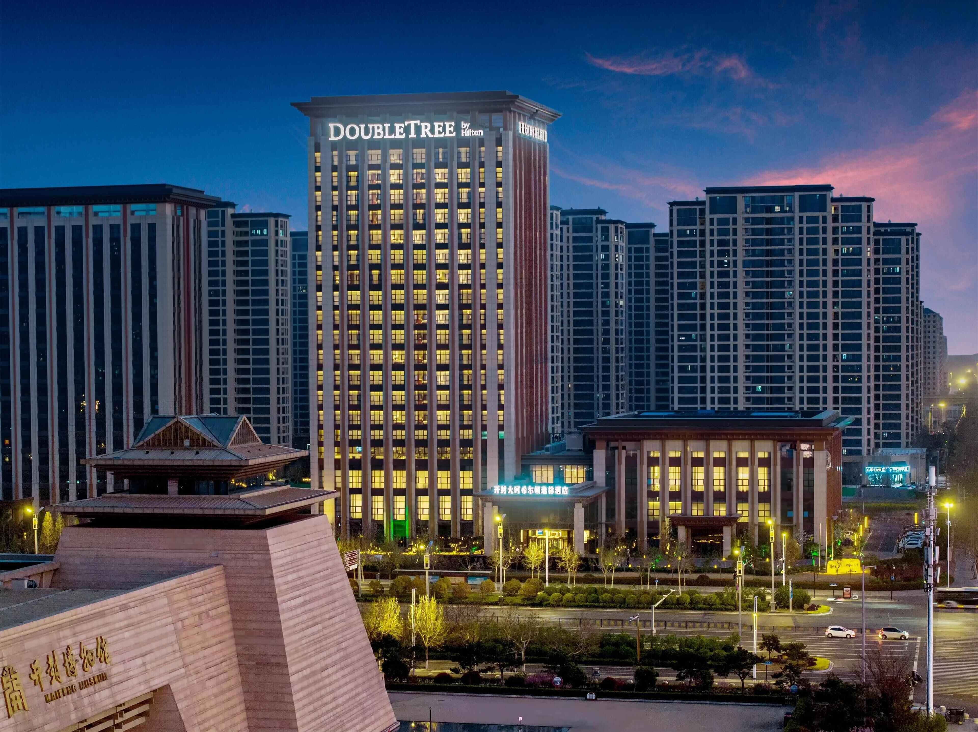A hotel named "DOUBLETREE by Hilton" with a modern design, surrounded by other high-rise buildings.