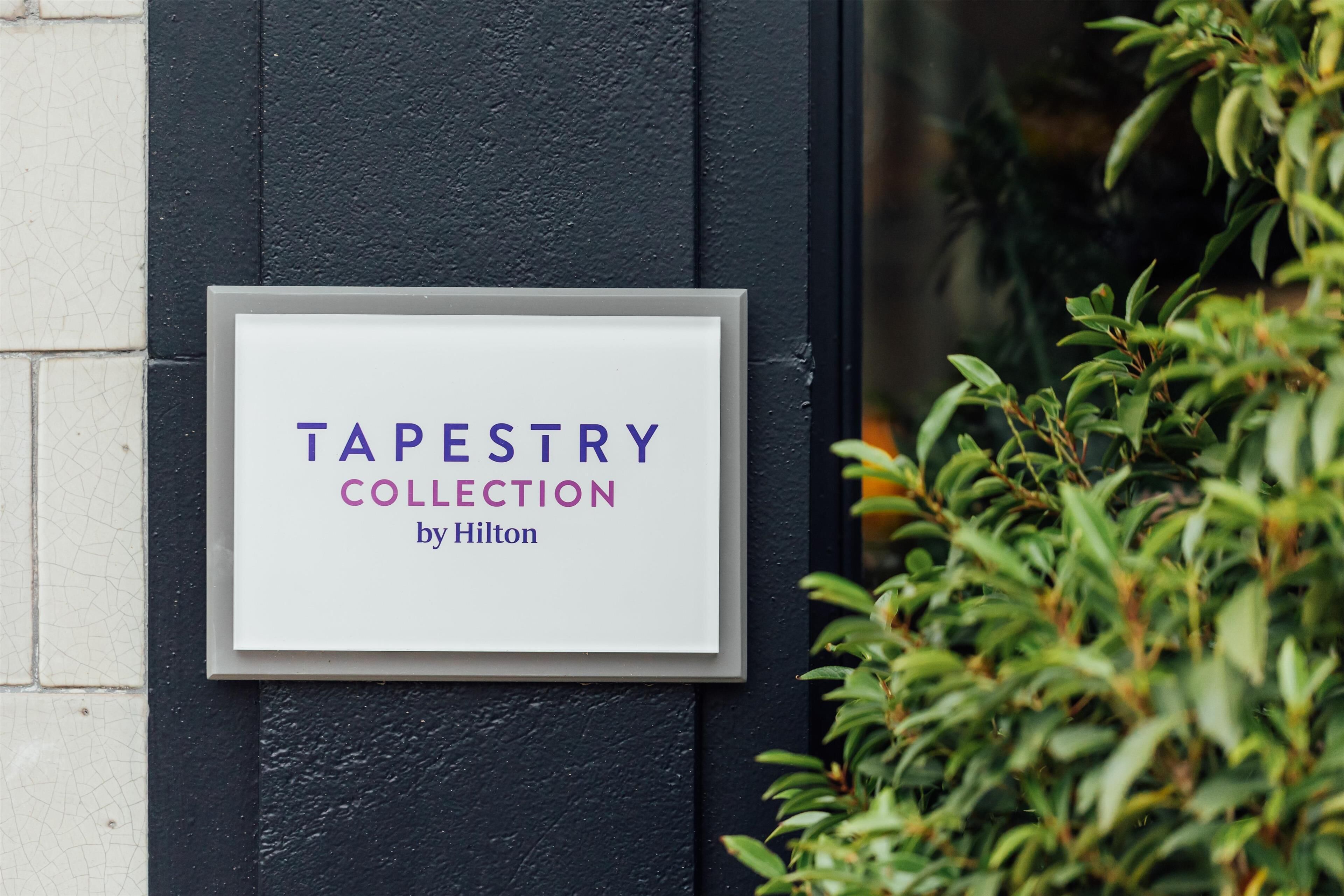 Un letrero en una pared que dice "TAPESTRY COLLECTION by Hilton".