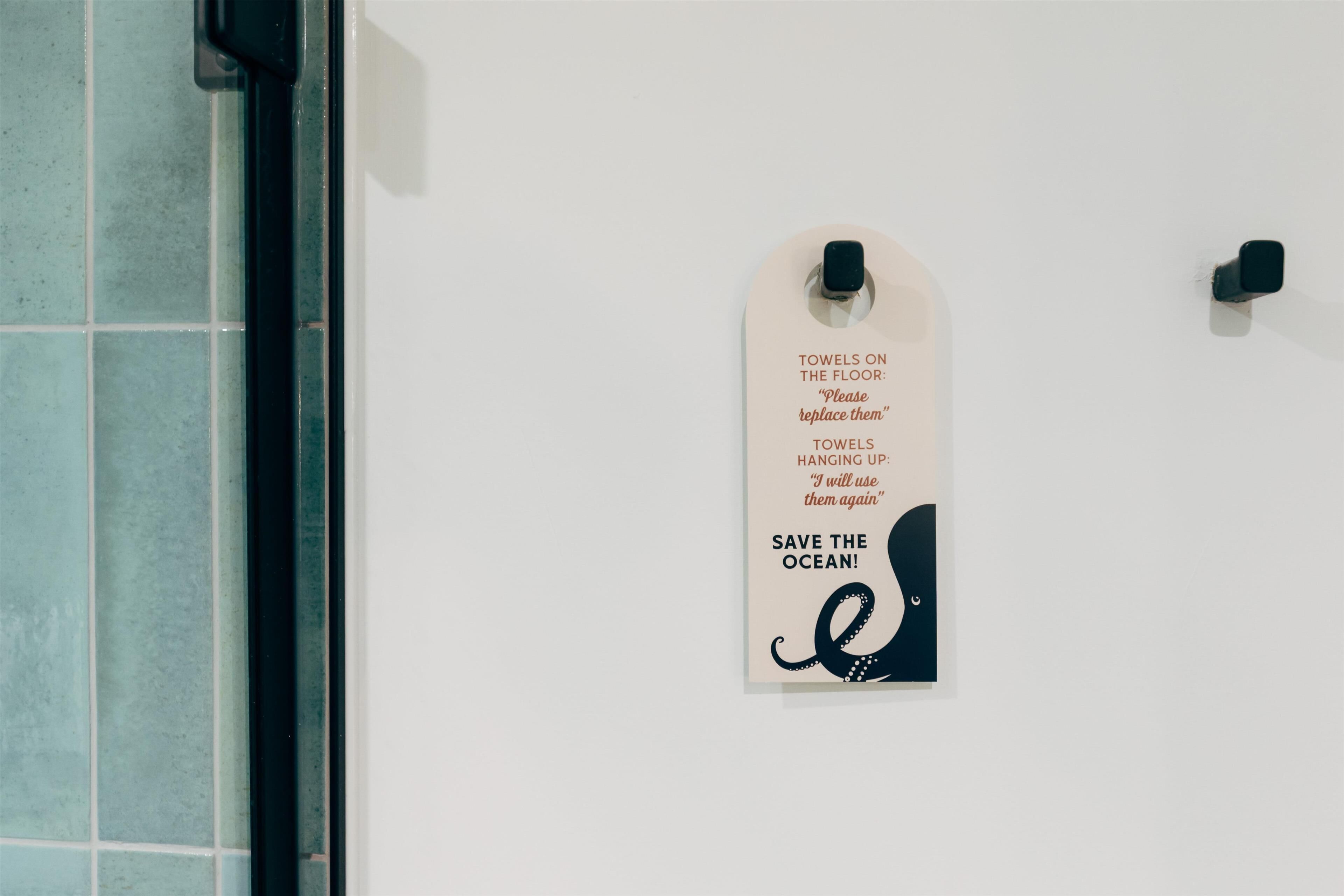 A wall with a sign instructing to replace towels on the floor and hang towels up.