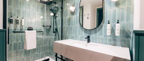 A modern bathroom with a glass-enclosed shower, a white marble sink, and a large mirror.