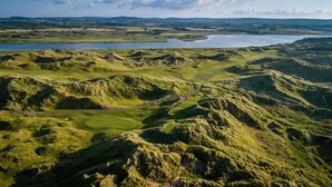 An aerial view of a golf course with undulating terrain and a winding path. - The Marcus Portrush, Tapestry Collection by Hilton (Portrush)