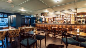 A bar area with wooden furniture, a bar counter, and various bottles and glasses. - The Marcus Portrush, Tapestry Collection by Hilton (Portrush)