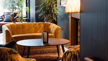 A cozy lounge area with a yellow sofa, a round table, and a patterned rug.