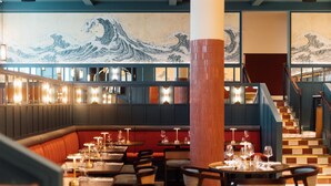A restaurant with booths, tables, and a large wave painting on the wall. - The Marcus Portrush, Tapestry Collection by Hilton (Portrush)