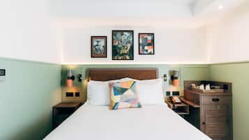 A hotel room with a large bed, a wooden headboard, bedside tables with lamps, and artwork on the wall.