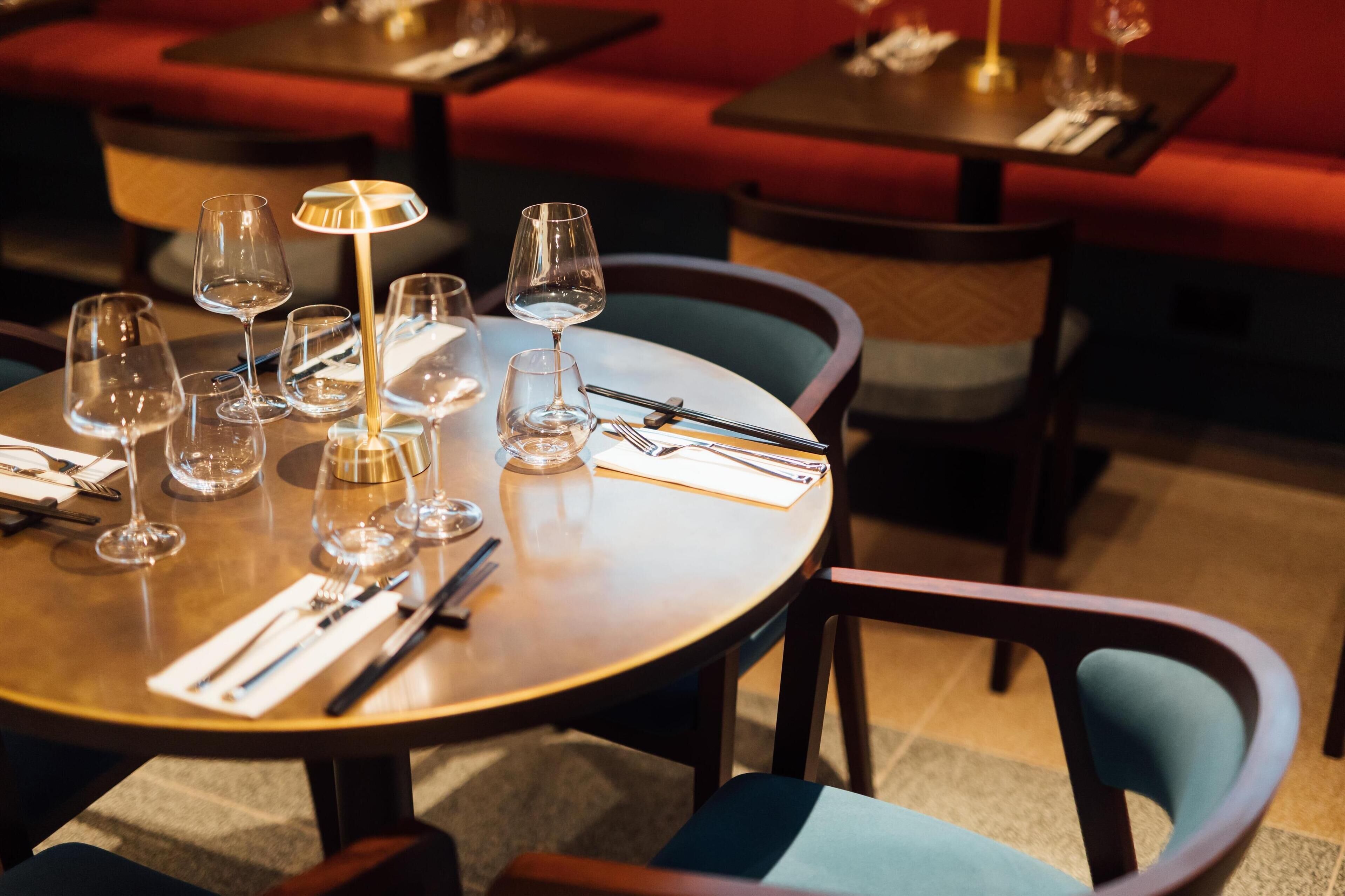 A restaurant setting with round tables, chairs, and empty wine glasses.