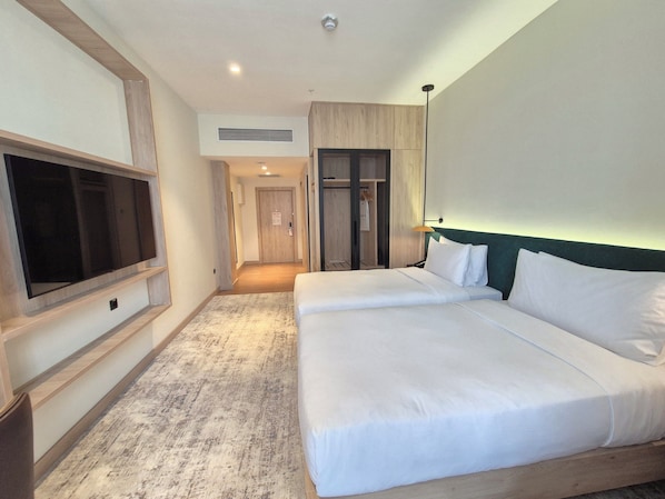 Una habitación de hotel con una cama grande, un televisor montado en la pared y un vestidor.