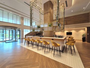Zona de bar moderna con una isla central, taburetes y una escalera con barandilla.
