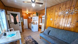 A cozy cabin interior with a dining area, kitchenette, and a sofa. - Cozy 2BR 1BA Cabin #6 Riverside Point Resort (Park Rapids)