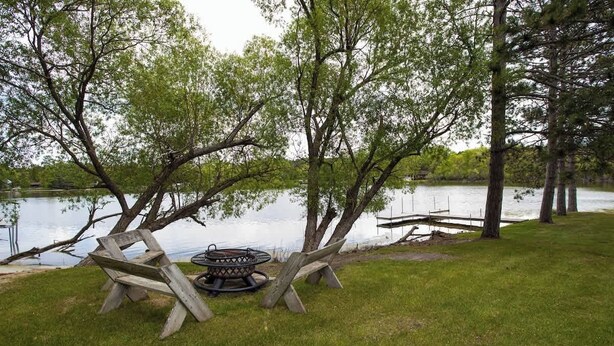 A lakeside picnic area with a fire pit and benches. - Cozy 2BR 1BA Cabin #6 Riverside Point Resort (Park Rapids)