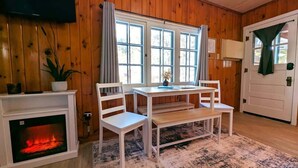 A cozy room with a fireplace, wooden walls, a table with chairs, and a television mounted on the wall. - Cozy 2BR 1BA Cabin #6 Riverside Point Resort (Park Rapids)