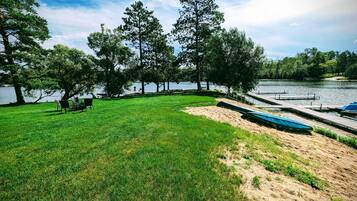 Zona verde con un muelle y barcos, rodeada de árboles y una masa de agua.