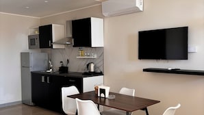 A modern kitchen with a dining area, featuring a flat-screen TV, a microwave, a refrigerator, and a coffee machine. - IG - Villa Don Antonio  Apartment  (Giardini Naxos)