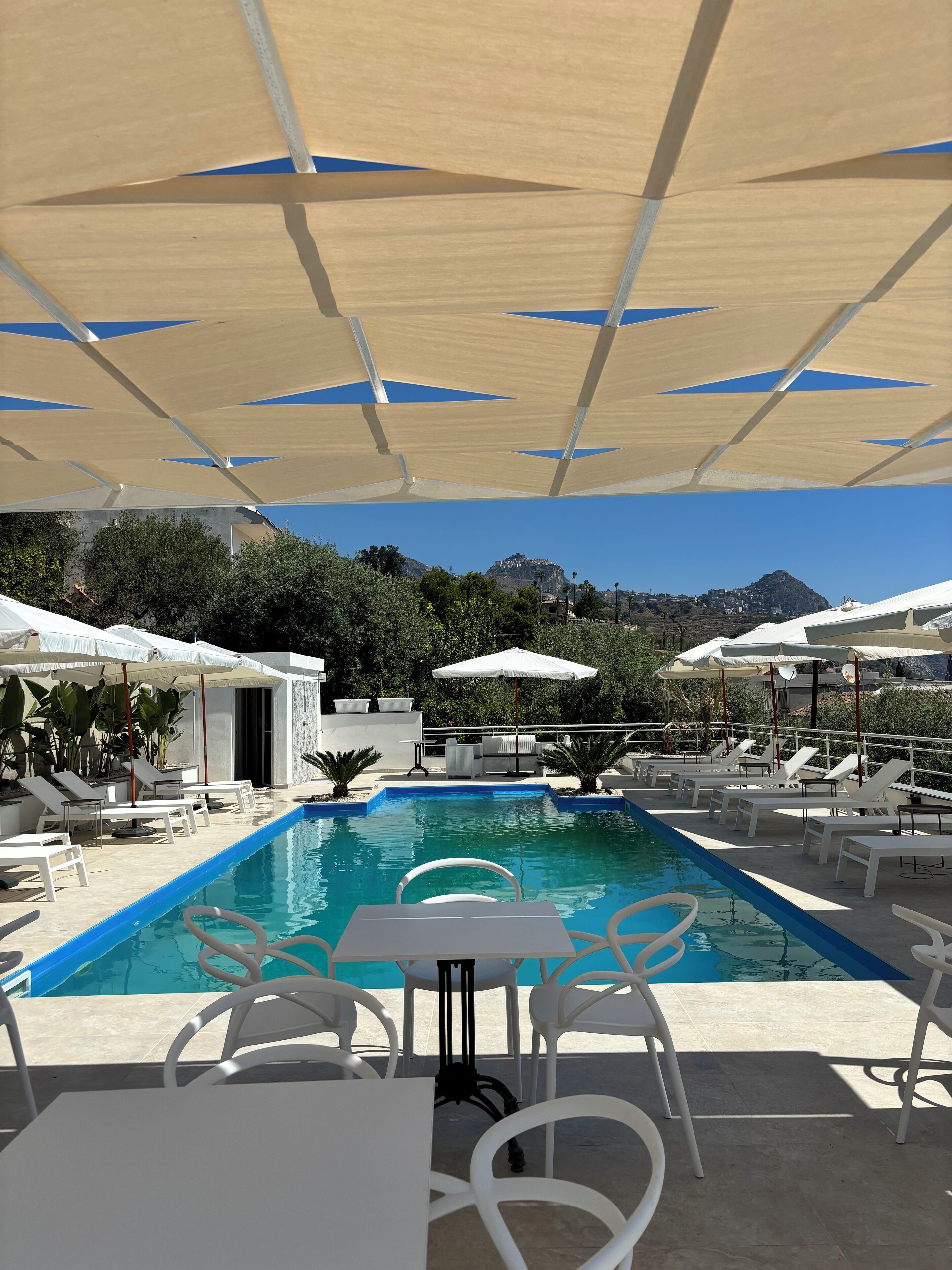 Un espace aménagé au bord de la piscine, avec des chaises longues, des parasols et une vue dégagée sur le paysage environnant.