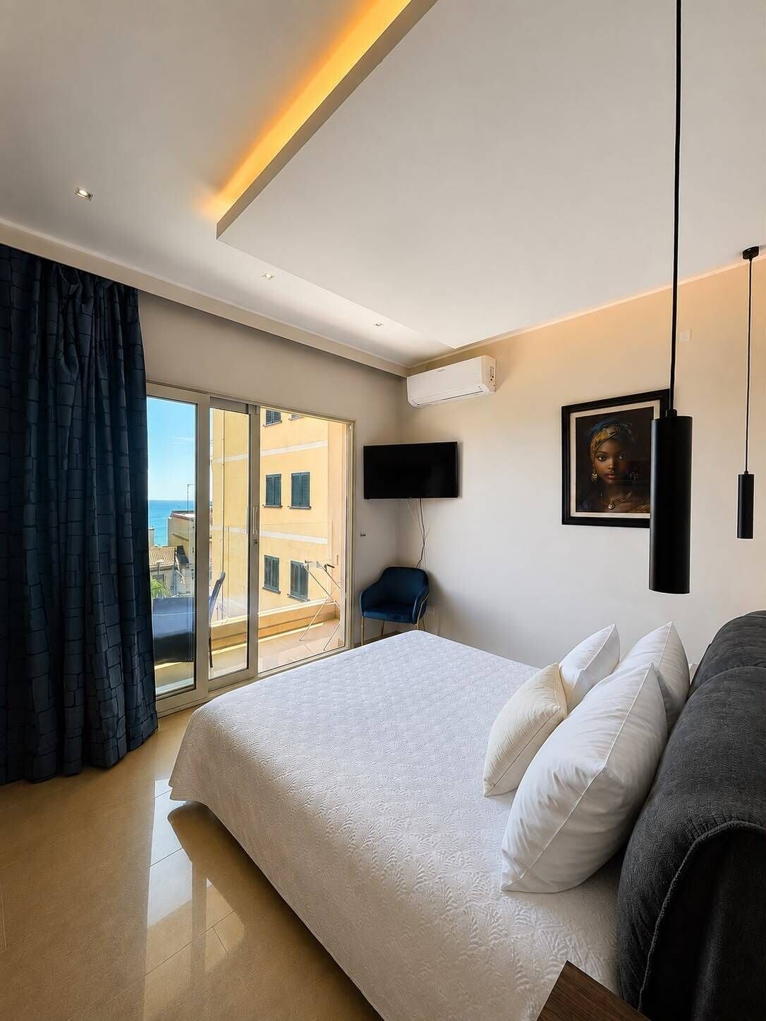 A modern bedroom with a large bed, a flat-screen TV, an air conditioning unit, and a view through a sliding glass door.