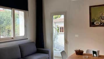 Un salon moderne avec un canapé, une table à manger, des chaises et une fenêtre.