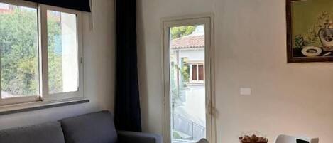 Ein modernes Wohnzimmer mit einer Couch, einem Esstisch, Stühlen und einem Fenster.