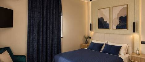 Un dormitorio moderno con una cama grande, un televisor y una zona de estar con un sillón.