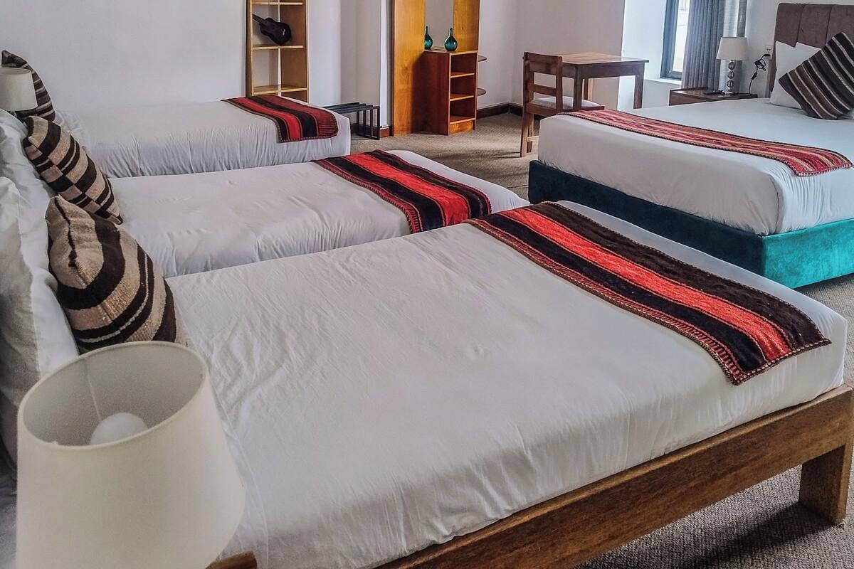 A hotel room with two beds, a desk, a chair, a lamp, and a wardrobe.