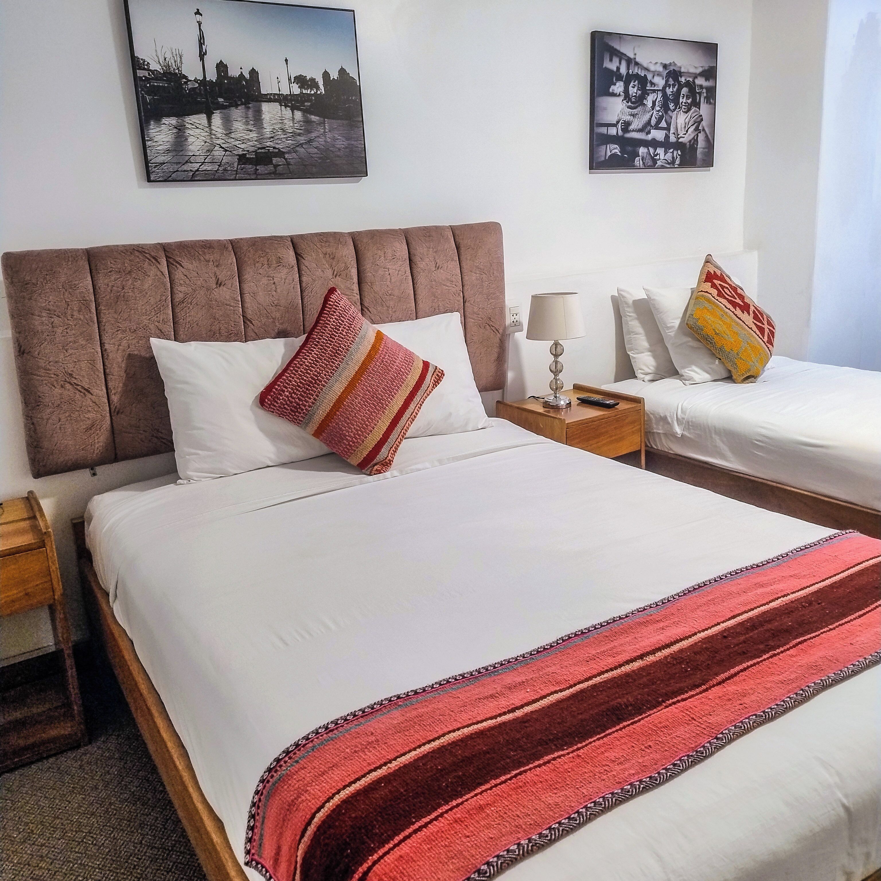 Een hotelkamer met twee bedden, een nachtkastje met een lamp en kunst aan de muren.