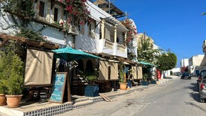 A street with buildings, outdoor seating, and potted plants. - Room Sidi bou Said (Hergla)
